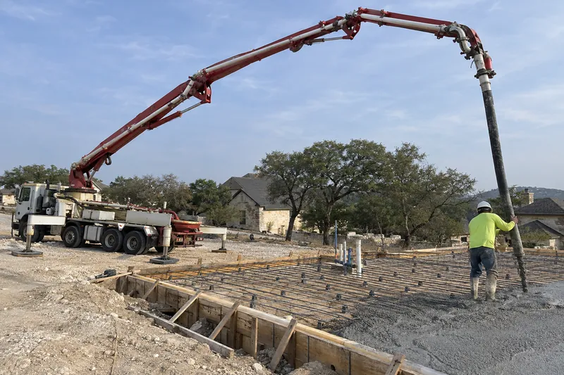Boom pump's arm reaching over a site, placing concrete