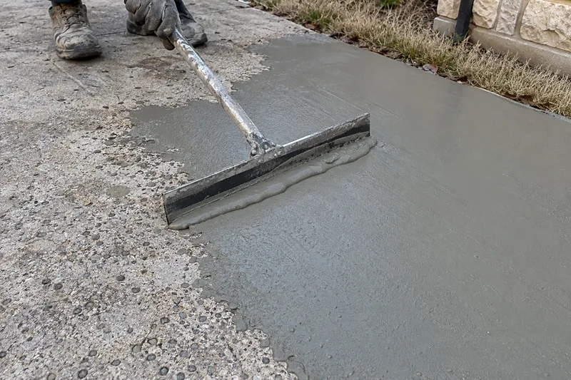 Cement resurfacer being spread over worn concrete with a squeegee