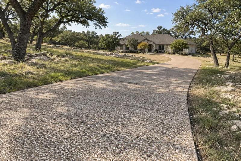 A long exposed-aggregate driveway at a home on acreage