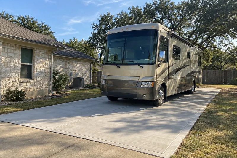 RV parked on a new concrete pad beside a house