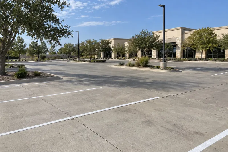 A shopping-centre concrete parking lot with fresh striping and light poles
